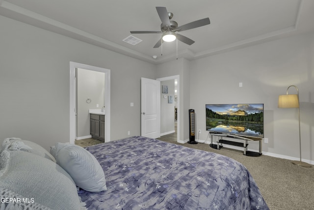 bedroom featuring a raised ceiling, ceiling fan, carpet floors, and ensuite bath