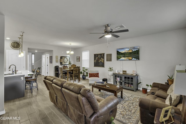 living room featuring sink, ceiling fan with notable chandelier, and hardwood / wood-style flooring