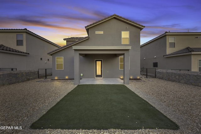 back house at dusk with a yard and a patio area