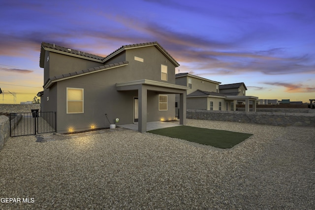 back house at dusk featuring a patio area