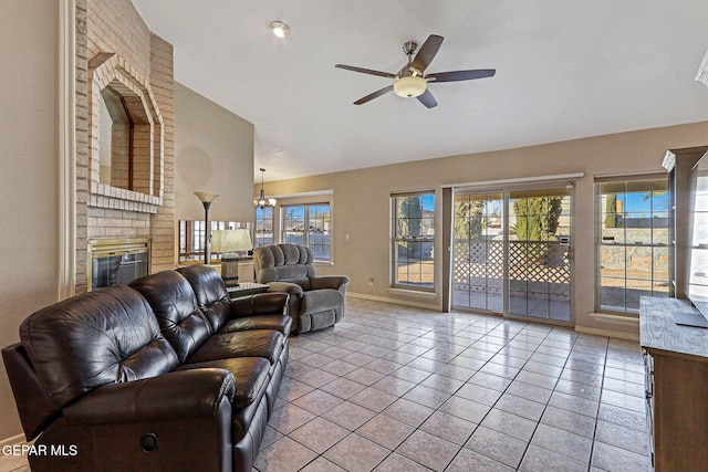 living room with lofted ceiling, ceiling fan with notable chandelier, a fireplace, and light tile patterned flooring