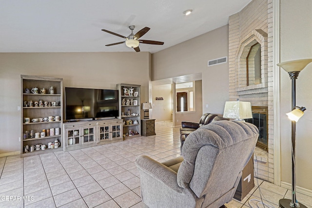 tiled living room featuring a fireplace, vaulted ceiling, and ceiling fan