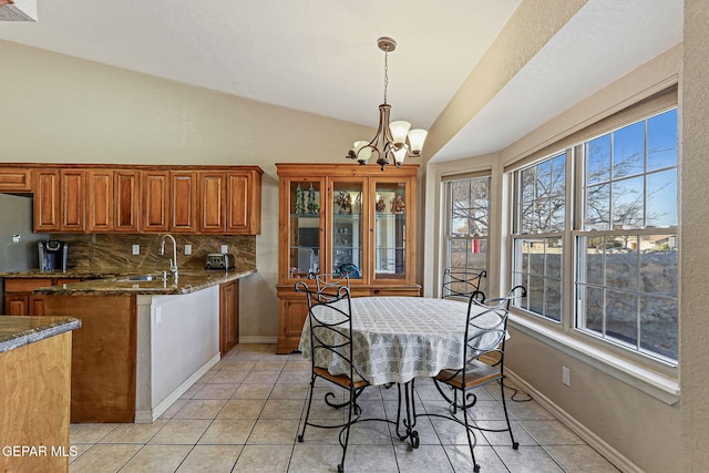 kitchen with vaulted ceiling, dark stone countertops, a chandelier, decorative backsplash, and hanging light fixtures