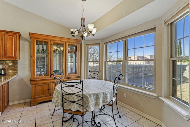 dining area with light tile patterned flooring, a chandelier, and vaulted ceiling