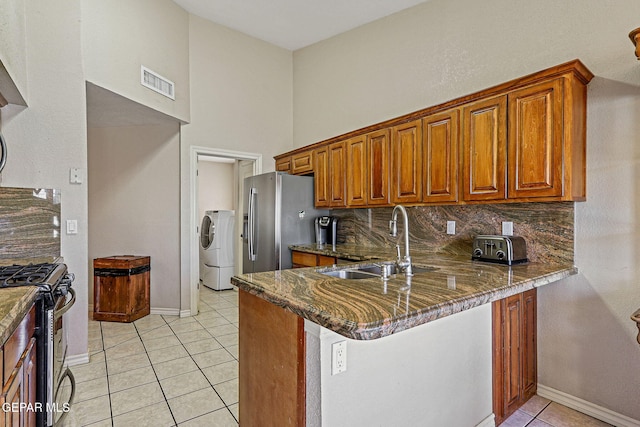 kitchen with sink, light tile patterned floors, appliances with stainless steel finishes, kitchen peninsula, and dark stone counters