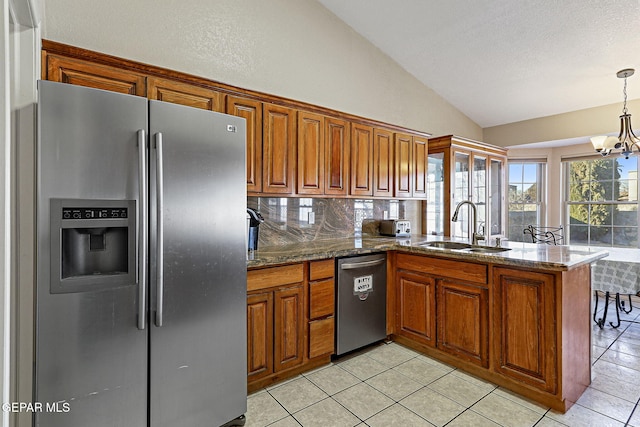 kitchen with sink, vaulted ceiling, hanging light fixtures, appliances with stainless steel finishes, and kitchen peninsula