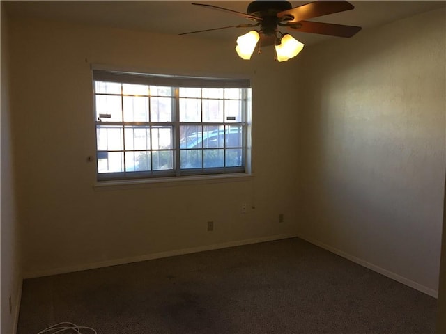 spare room featuring ceiling fan, plenty of natural light, and dark carpet