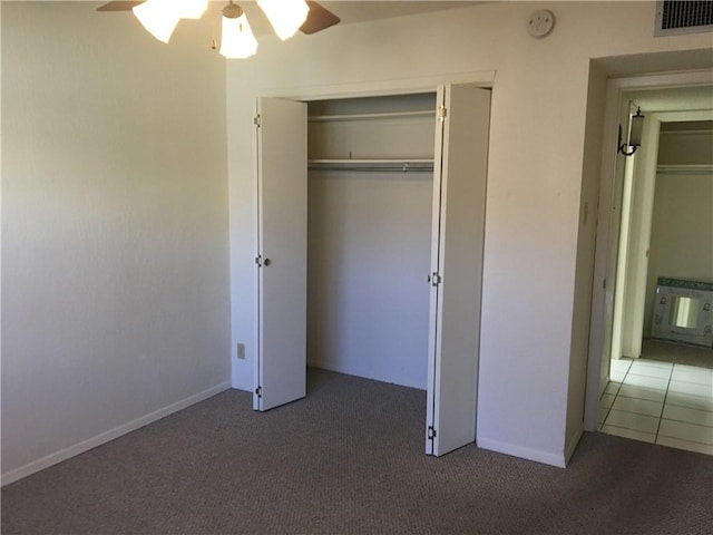 unfurnished bedroom with dark carpet, a closet, and ceiling fan