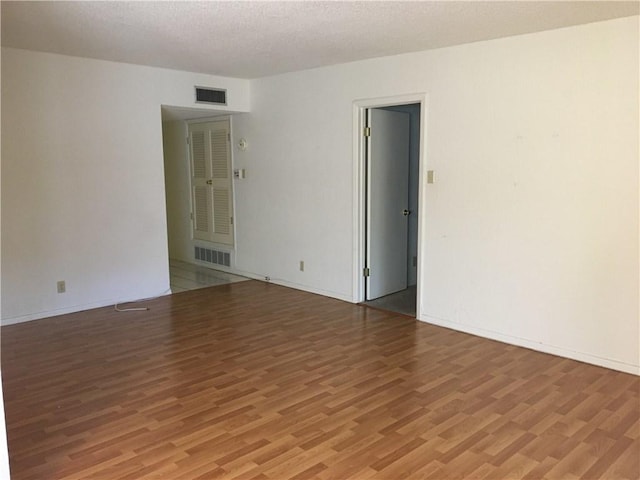 spare room featuring hardwood / wood-style floors and a textured ceiling