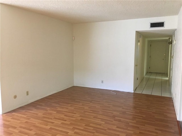 spare room featuring wood-type flooring and a textured ceiling