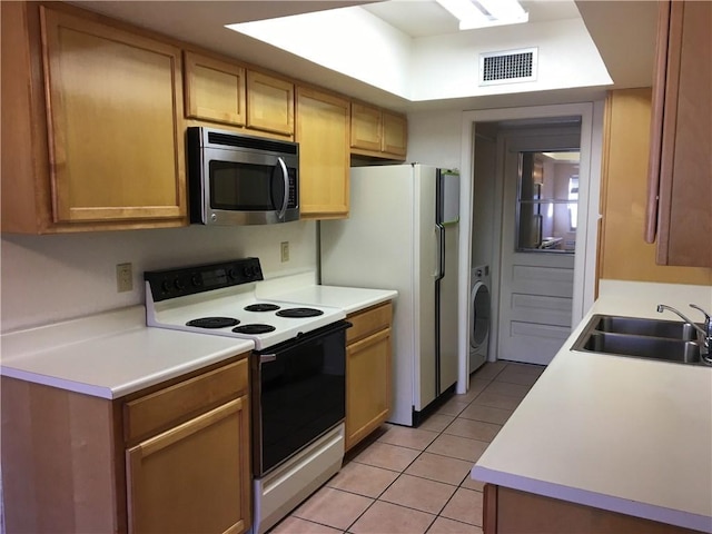 kitchen featuring sink, white appliances, washer / dryer, and light tile patterned floors