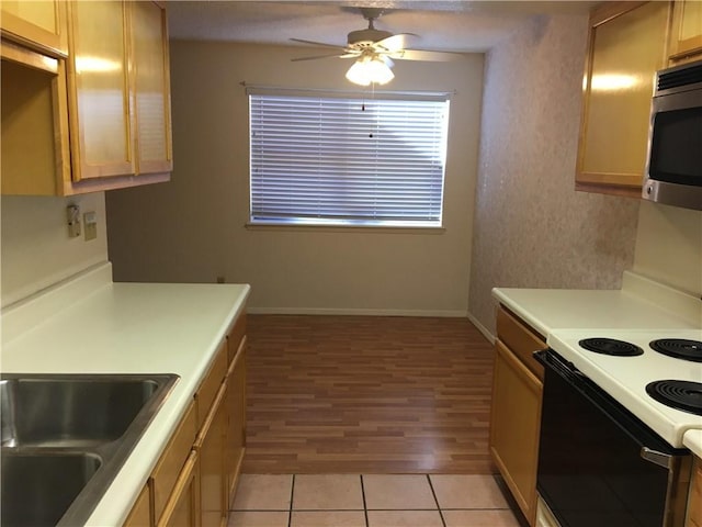 kitchen with electric stove, sink, and light brown cabinets