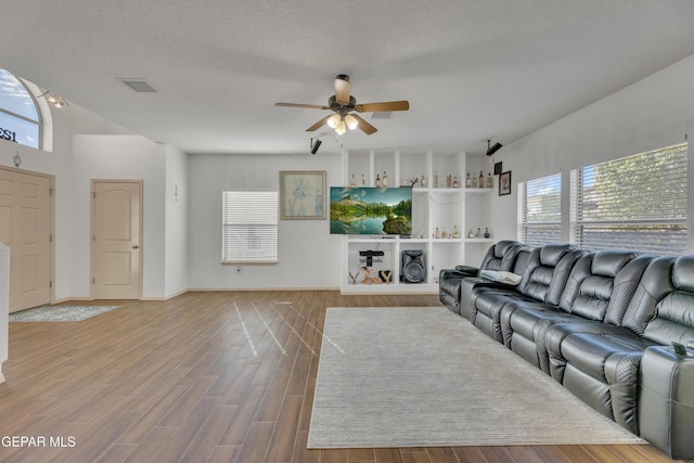 living room featuring ceiling fan, a wealth of natural light, wood-type flooring, and a textured ceiling