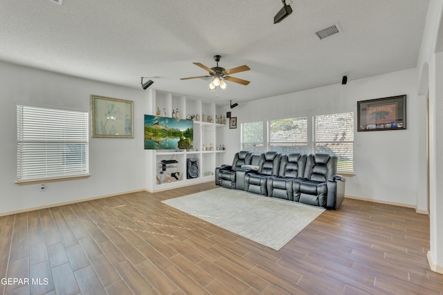 living room featuring ceiling fan, a textured ceiling, and light wood-type flooring