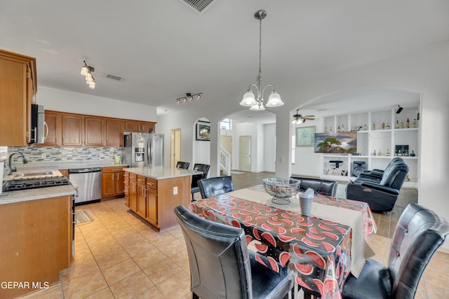 kitchen with pendant lighting, sink, appliances with stainless steel finishes, backsplash, and a kitchen island