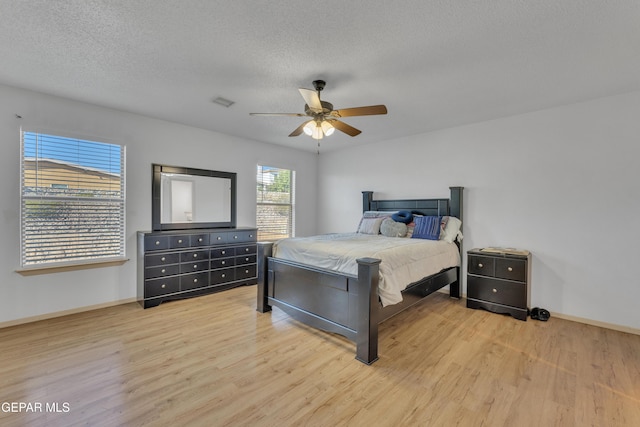 bedroom featuring ceiling fan, light hardwood / wood-style flooring, and a textured ceiling