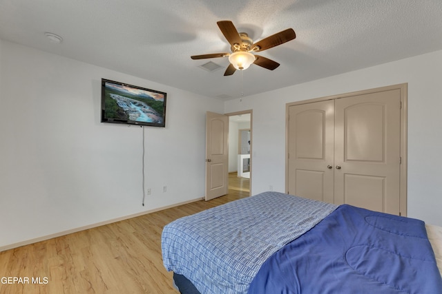 bedroom featuring ceiling fan, wood-type flooring, a closet, and a textured ceiling