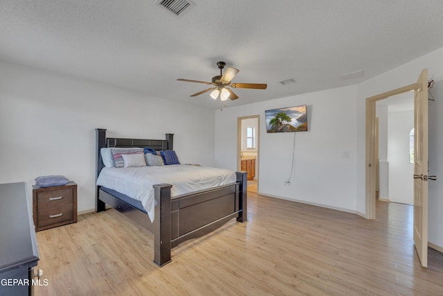 bedroom with ceiling fan, a textured ceiling, and light hardwood / wood-style floors