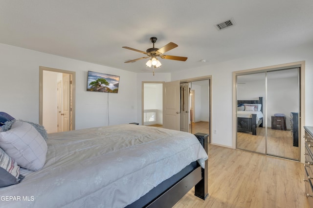 bedroom with two closets, light hardwood / wood-style floors, and ceiling fan