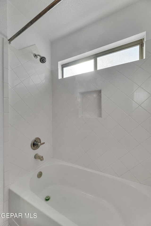 bathroom with tiled shower / bath combo and a textured ceiling