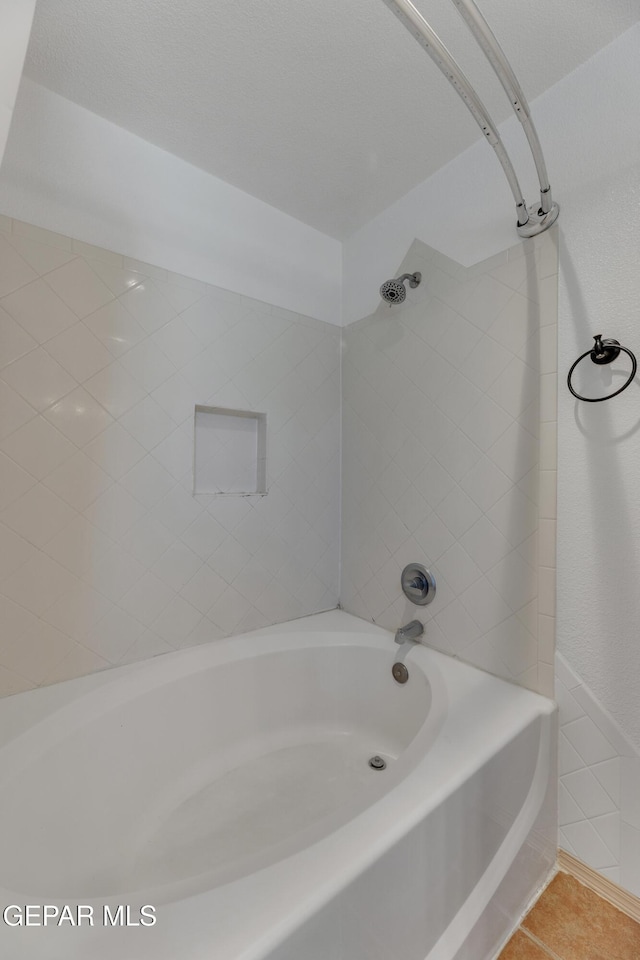 bathroom featuring tile patterned flooring and tiled shower / bath