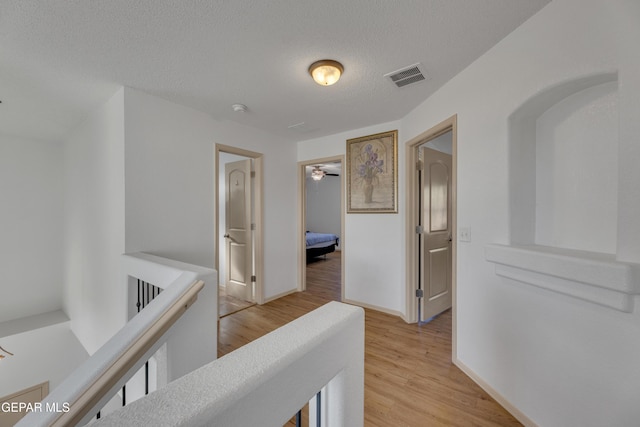 hall featuring light hardwood / wood-style flooring and a textured ceiling