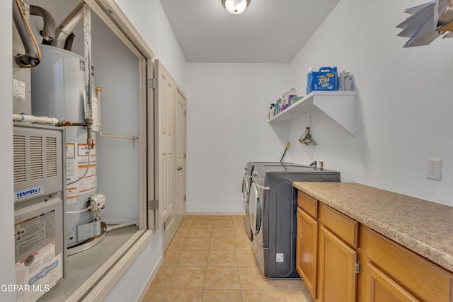 laundry area with cabinets, washing machine and clothes dryer, gas water heater, and light tile patterned floors