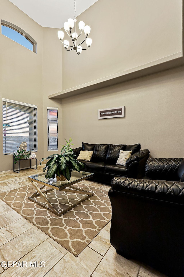 living room featuring a healthy amount of sunlight, a towering ceiling, and a chandelier