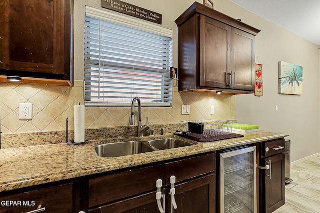 kitchen featuring light stone counters, sink, tasteful backsplash, and beverage cooler