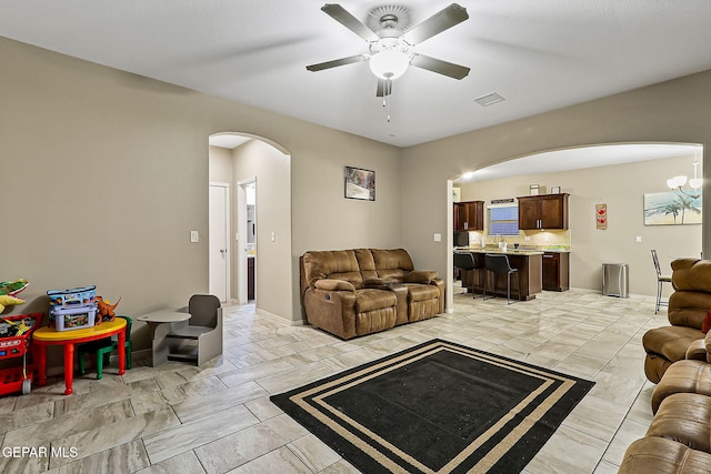 living room featuring ceiling fan with notable chandelier