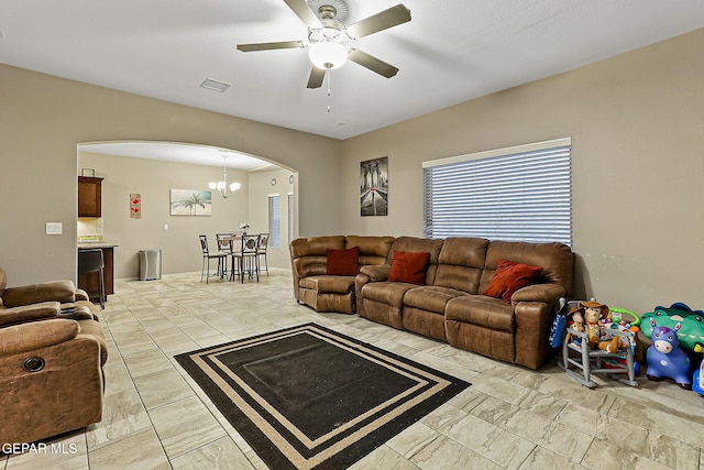 living room with ceiling fan with notable chandelier