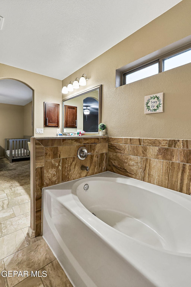 bathroom with a washtub and a textured ceiling