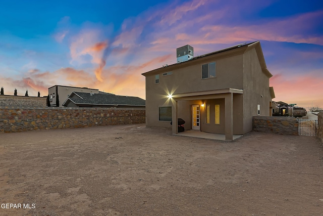 back house at dusk with cooling unit and a patio