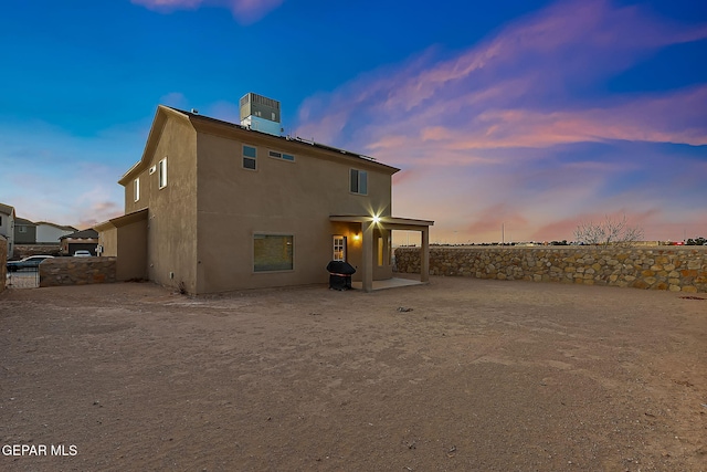 back house at dusk featuring central AC