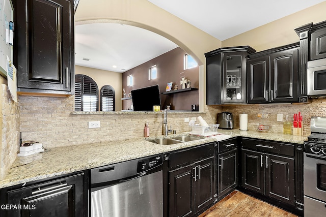 kitchen featuring light hardwood / wood-style flooring, light stone countertops, sink, appliances with stainless steel finishes, and decorative backsplash