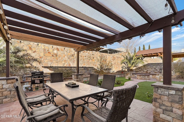 view of patio with grilling area, a pergola, and a fire pit