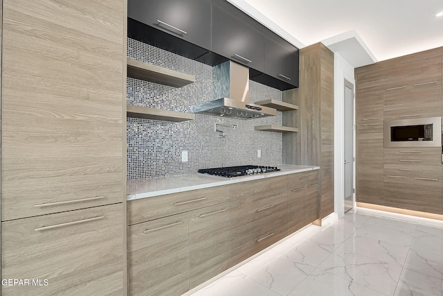 kitchen with built in microwave, wall chimney range hood, tasteful backsplash, and stainless steel gas cooktop