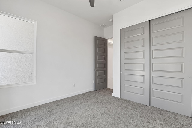 unfurnished bedroom with light colored carpet and a closet