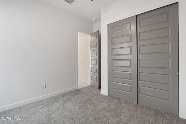 unfurnished bedroom featuring light carpet and a closet