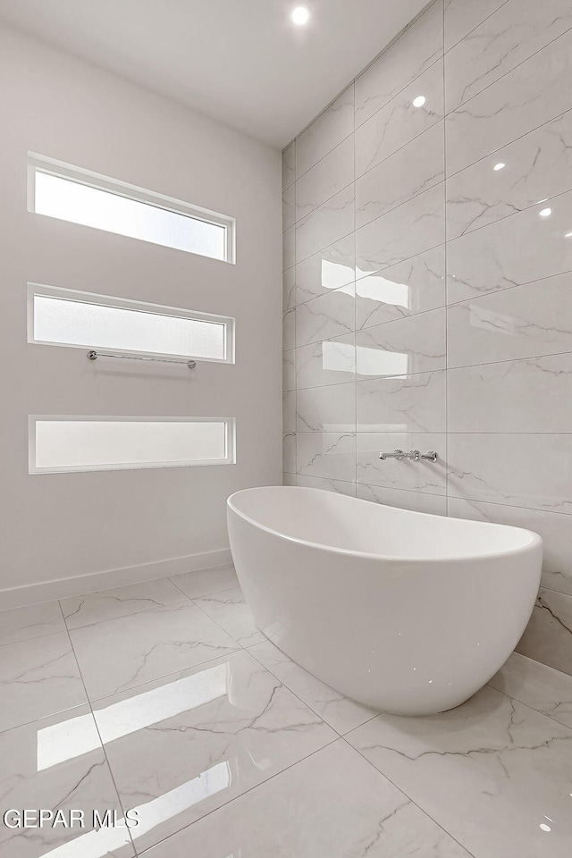 bathroom with a bathtub and tile walls