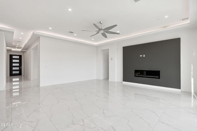 unfurnished living room featuring ceiling fan and a tray ceiling