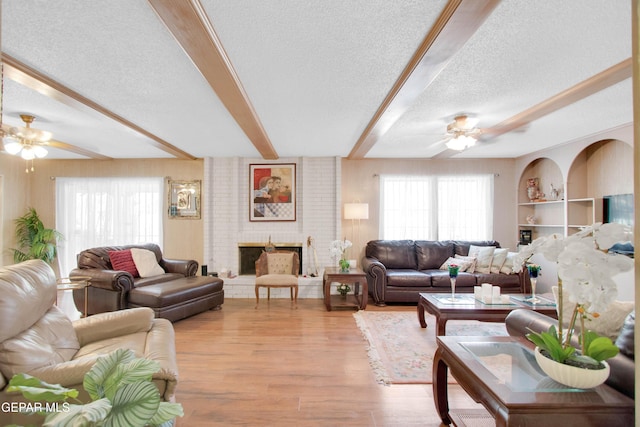 living room featuring a healthy amount of sunlight, ceiling fan, beamed ceiling, and a textured ceiling