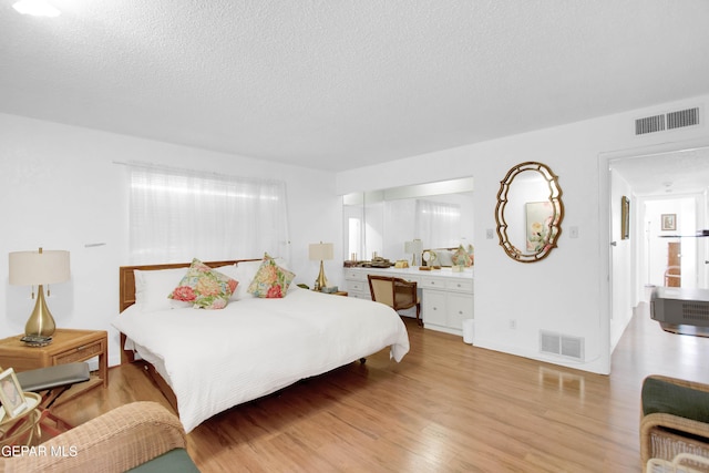 bedroom featuring a textured ceiling and light hardwood / wood-style flooring