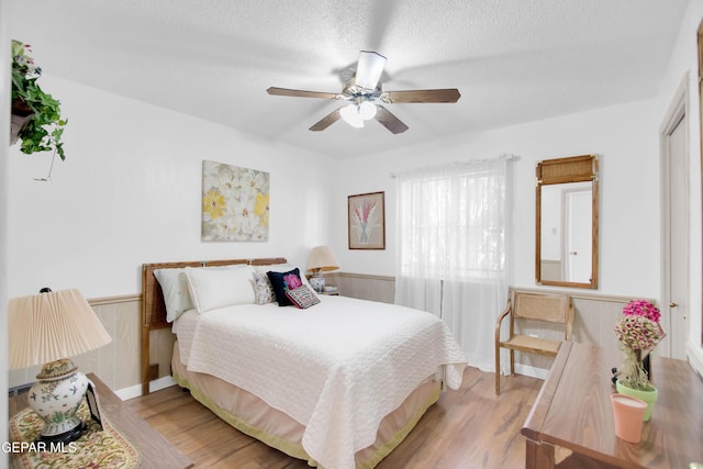 bedroom with ceiling fan, light hardwood / wood-style flooring, and a textured ceiling