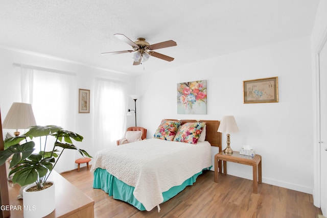 bedroom featuring ceiling fan, wood-type flooring, and a textured ceiling