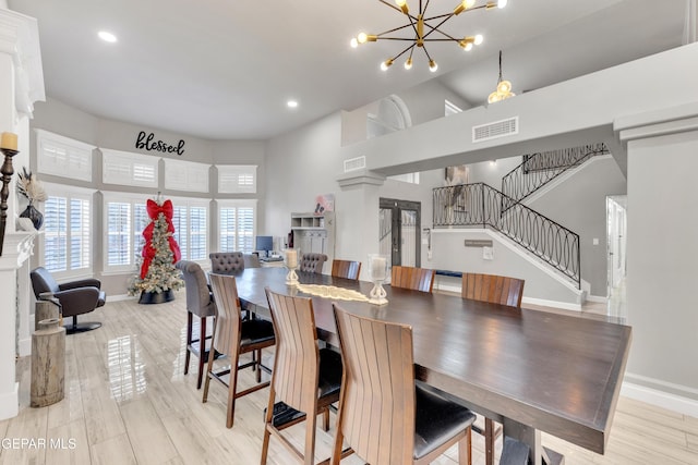 dining area featuring an inviting chandelier, high vaulted ceiling, and light wood-type flooring