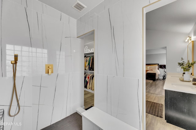 bathroom featuring vanity, vaulted ceiling, wood-type flooring, and tile walls