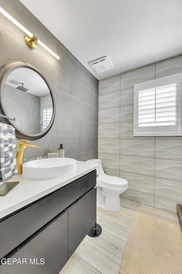 bathroom with decorative backsplash, vanity, toilet, and tile walls