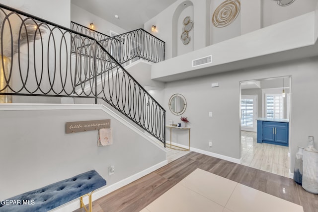 staircase featuring a towering ceiling and hardwood / wood-style floors