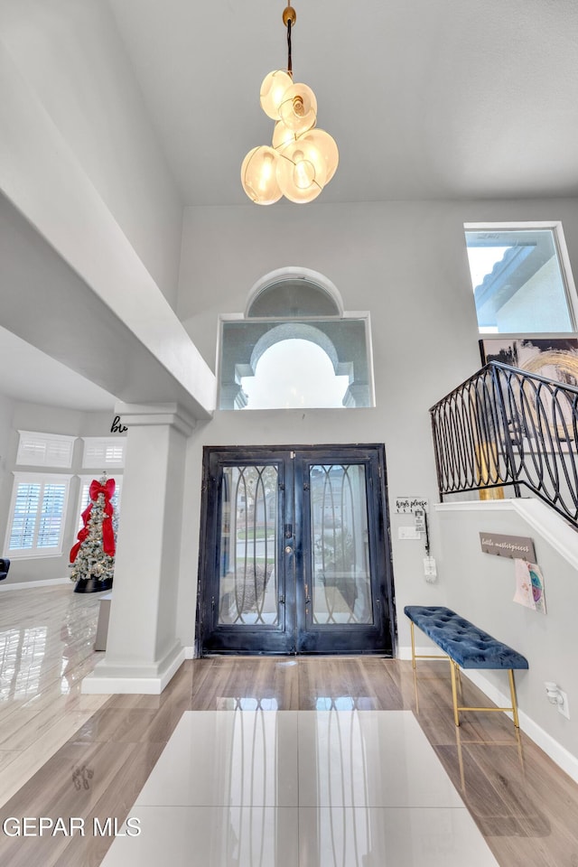 foyer with high vaulted ceiling, a healthy amount of sunlight, and hardwood / wood-style floors